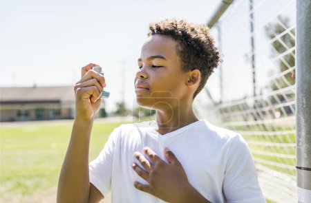 Un enfant utilise un inhalateur d'asthme dans le parc