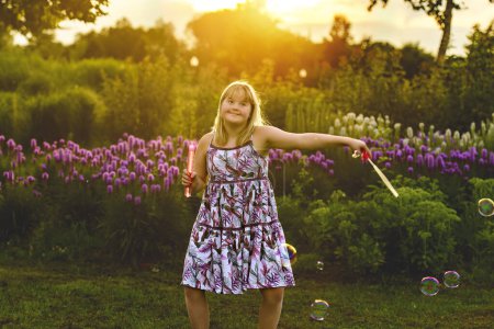 A portrait of child girl outside in summer season at the sunset with bubble