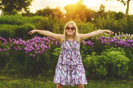 A portrait of child girl outside in summer season at the sunset with love sunglasses