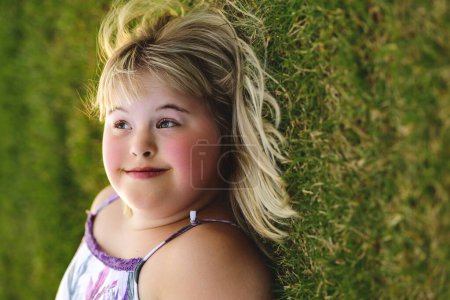 A portrait of child girl outside in summer season at the sunset lay on the grass