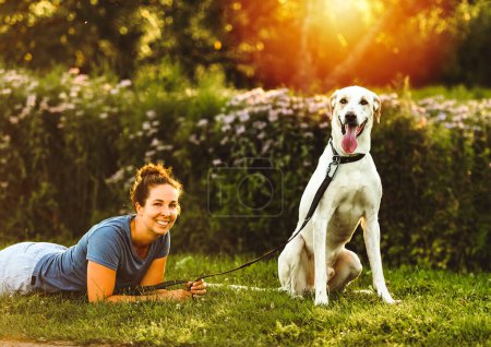 Eine Frau und ihr befreundeter Hund vor dem Hintergrund des Sonnenuntergangs