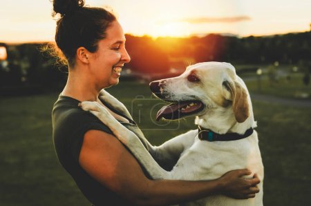 Eine Frau und ihr befreundeter Hund vor dem Hintergrund des Sonnenuntergangs