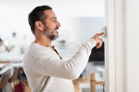 Un homme a mis le thermostat à la maison
