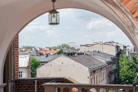 Vintage Latarnia z widokiem na dachy Starego Miasta, wyjątkowa perspektywa zabytkowych dachów miasta, oprawione eleganckim łukiem z klasyczną latarnią wiszącą nad.