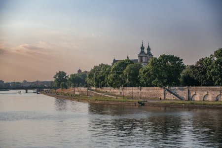 Spokojna Wisła z Wawel Castle in the Distance, spokojnym pięknem Wawel Castle widocznym z brzegu Wisły w Krakowie podczas ciepłych, złotych godzin zachodu słońca.