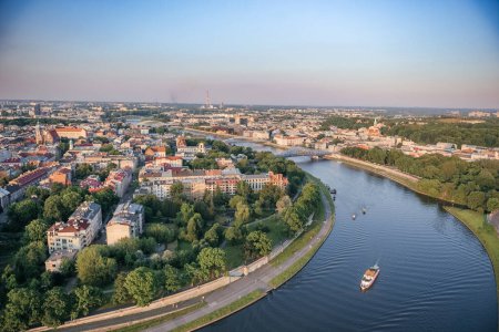 Widok z powietrza na zachód słońca nad Krakowem: Pejzaż miejski i drogi wodne z góry, zachód słońca nad Krakowem, z rzeką Wisłą elegancko zakrzywioną przez krajobraz miasta.
