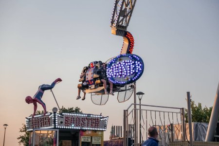Photo for Thrill-Seekers on Amusement Park Ride at Dusk, an exhilarating amusement park ride, with bright lights adding a festive glow to the adventurous atmosphere - Royalty Free Image