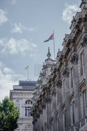 Detaillierte Ansicht eines historischen Londoner Gebäudes mit kunstvoller Architektur, mit Union-Jack-Flagge, ukrainischer Flagge und blauem Himmel