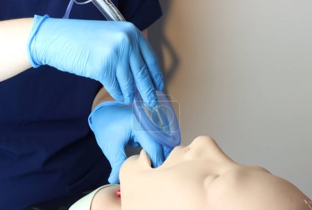 Téléchargez les photos : Masque laryngé voies respiratoires (LMA) Béring inséré dans les voies respiratoires d'un patient simulé par un professionnel de la santé portant des gants et des gommages chirurgicaux - en image libre de droit