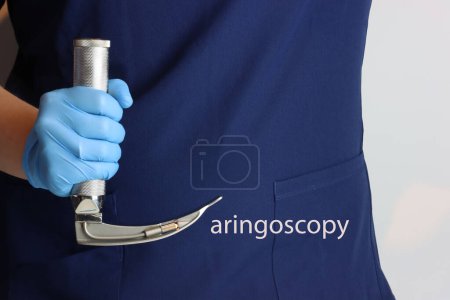Téléchargez les photos : Laryngoscope dans les mains d'un professionnel de la santé regardant comme une lettre L et le mot laryngoscopie a été représenté - en image libre de droit