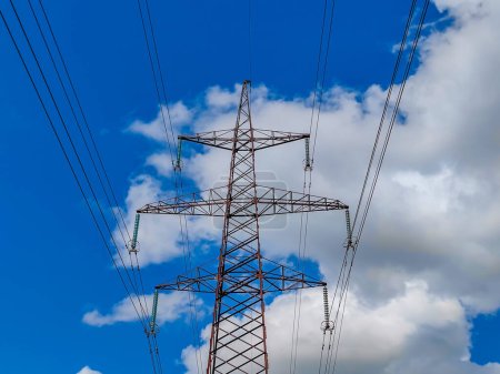 High voltage line poles and wires with blue sky and white clouds background