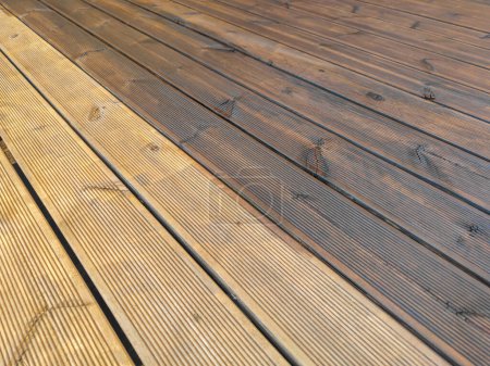 Foto de Parcialmente pintado y parcialmente limpiado terraza de madera estriada impregnada de aceite. Decking de tablones de madera - Imagen libre de derechos