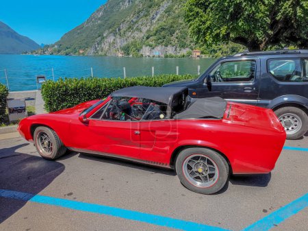 Téléchargez les photos : Une vieille voiture convertible rouge classique garée sur la rive du lac de Lugano en Italie - en image libre de droit