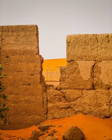 Idyllischer Blick auf die Sahara durch eine Lücke in einer alten Mauer in Merzougha, Marokko