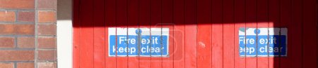 Téléchargez les photos : Sortie incendie garder signe clair sur la porte du chantier de construction Royaume-Uni - en image libre de droit