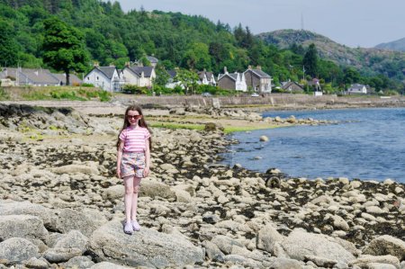 Téléchargez les photos : Joyeux jeune fille sur la plage de Tighnabruaich en Argyll et Bute sur la côte ouest de l'Écosse pendant l'été Royaume-Uni - en image libre de droit
