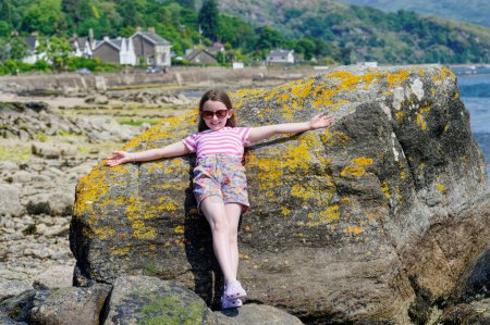 Téléchargez les photos : Joyeux jeune fille sur la plage de Tighnabruaich en Argyll et Bute sur la côte ouest de l'Écosse pendant l'été Royaume-Uni - en image libre de droit