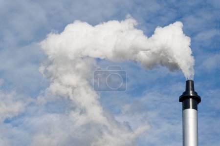 Photo for Flue chimney and smoke against blue sky UK - Royalty Free Image