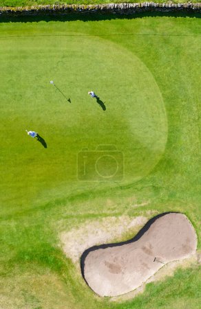 Golf course green aerial view and two players UK
