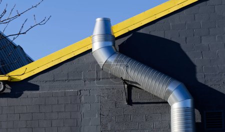 Photo for Flue chimney fixed to building exterior wall stainless steel from exhaust boiler plant room UK - Royalty Free Image