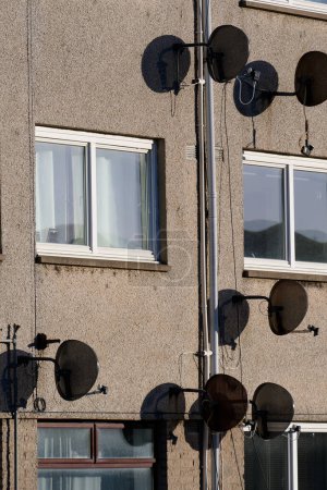 Satellite dish in group on wall of council house UK