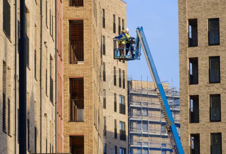 Foto de Elevador de tijera operado por trabajadores de la construcción para un acceso seguro a la altura - Imagen libre de derechos