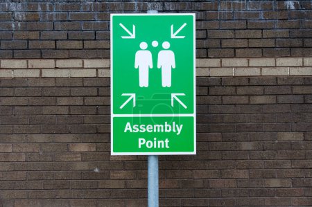 Fire assembly point sign at workplace signpost UK