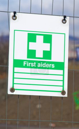 Construction site first aiders health and safety sign on fence UK