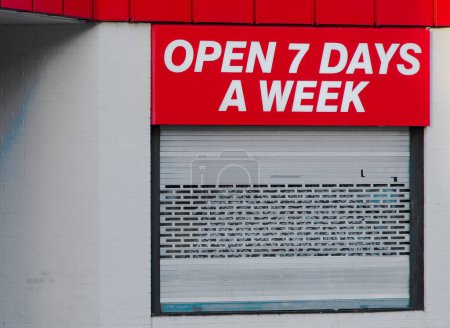 Open 7 days a week sign above business store front UK