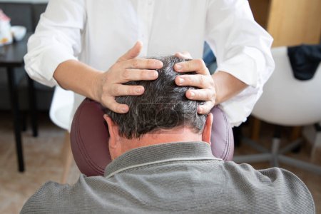Téléchargez les photos : Massothérapeute homme massant crâne masculin assis sur massage assis par une femme spécialiste sur chaise de massage du genou siège adapté - en image libre de droit