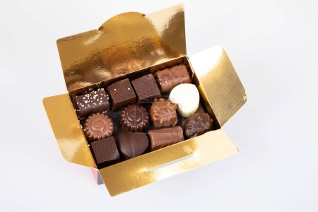 Sortiment feiner Pralinen-Bonbons in kleiner goldener Geschenkschachtel mit dunkler Vollmilchschokolade