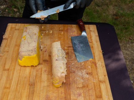 Chef de foie gras de canard prépare foie gras à couper en tranches sur la planche à découper en bois pour un événement