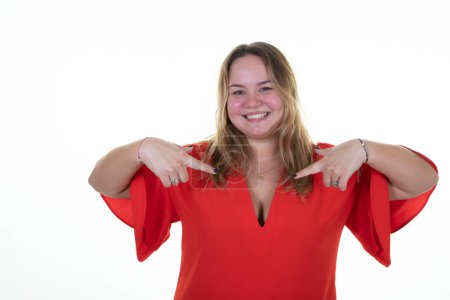 Téléchargez les photos : Overweight woman curvy blonde proud positive pointing to red chest with finger hands on white background - en image libre de droit