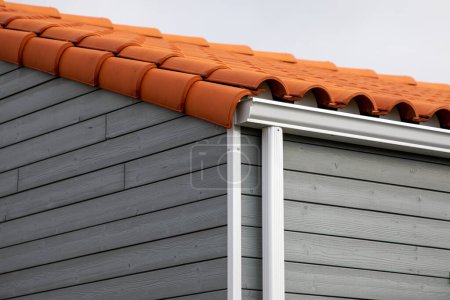 weiße Dachrinnenschutz-System Faszien Tropfkante auf einzelne graue hölzerne Einfamilienhaus Nachbarschaft