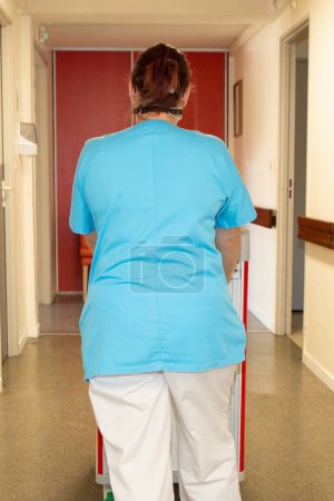 Téléchargez les photos : Infirmière médecin marchant à travers un long couloir intérieur à l'hôpital - en image libre de droit