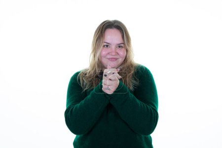 Téléchargez les photos : Les mains de femme en surpoids serrées serrées dans le pull d'hiver vert souriant et décontracté en fond blanc - en image libre de droit