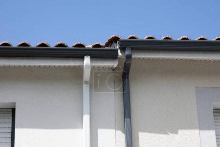 Téléchargez les photos : Bord blanc gris des gouttières de toit des maisons jumelées système de garde de gouttière en aluminium de bardeaux - en image libre de droit