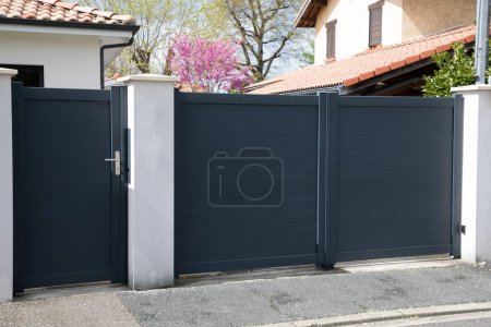 Foto de Portal puerta de metal gris alto en la entrada del jardín de la casa y poco peatonal puerta gris acceso - Imagen libre de derechos