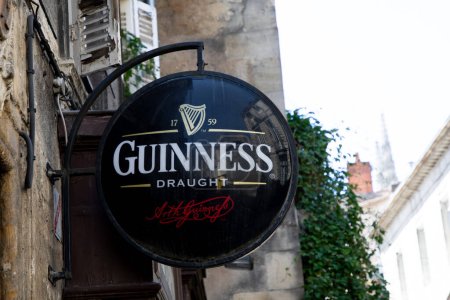 Foto de Burdeos, Aquitania Francia - 04 17 2023: guinness sign text and logo brand of irish beer on street entrance restaurante pub bar wall facade - Imagen libre de derechos