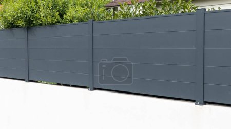 Téléchargez les photos : Mur barrière en aluminium gris et acier de clôture grise de maison individuelle privée moderne nouveau protéger vue jardin à la maison - en image libre de droit