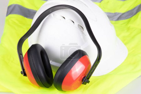 Téléchargez les photos : Équipement de protection individuelle pour la sécurité industrielle casque anti-bruit casque et veste de sécurité réfléchissante jaune sur fond blanc - en image libre de droit