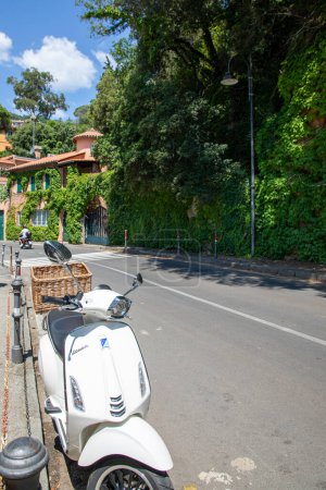Foto de Burdeos, Francia - 06 27 2023: vespa scooter a un lado de la carretera con bonitos invernaderos al fondo Marca italiana de scooter fabricado por Piaggio - Imagen libre de derechos
