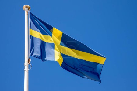 Téléchargez les photos : Drapeau scandinavie agitant de la Suède contre le ciel bleu en tissu bleu jaune couleurs croix - en image libre de droit