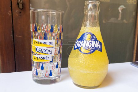 Foto de Burdeos, Francia - 09 22 2023: Letrero del logotipo carbonatado limonada naranja Orangina y texto de la marca en bootle con vidrio de marca de soda vacío - Imagen libre de derechos