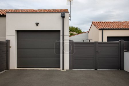 Téléchargez les photos : Maison moderne façade avec garage fermé porte gris foncé obturateur entrée voiture de maison privée - en image libre de droit