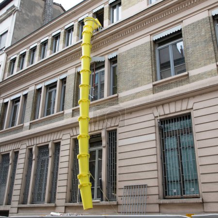Téléchargez les photos : Glissière en plastique jaune pour l'enlèvement des débris sur la façade du bâtiment en cours de rénovation chantier de construction dans la rue de la ville - en image libre de droit
