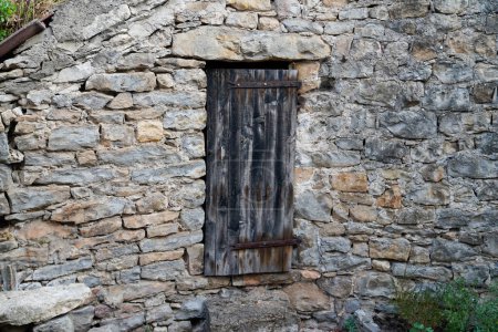 ancienne façade de ferme avec mur en pierre typique et fenêtre à volets en bois classique fermée du centre de la France caussenarde dans le village de Lozere Hures la Parade