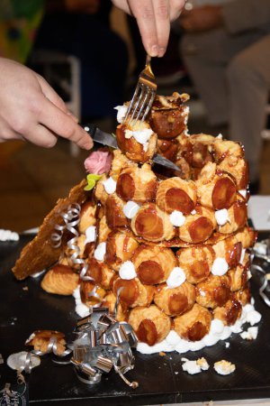 Pirámide de croquembouche con esmalte de caramelo sobre una mesa