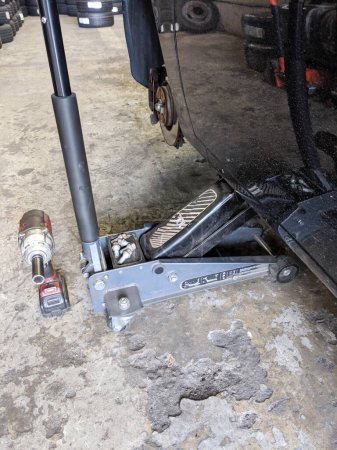 Auto mecánico jacks el coche en servicio de garaje de neumáticos