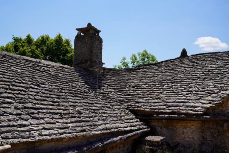 Téléchargez les photos : Tuiles de toit pierre grise de vieille ferme bâtiment médiéval avec fond de pierres gris cheminée - en image libre de droit